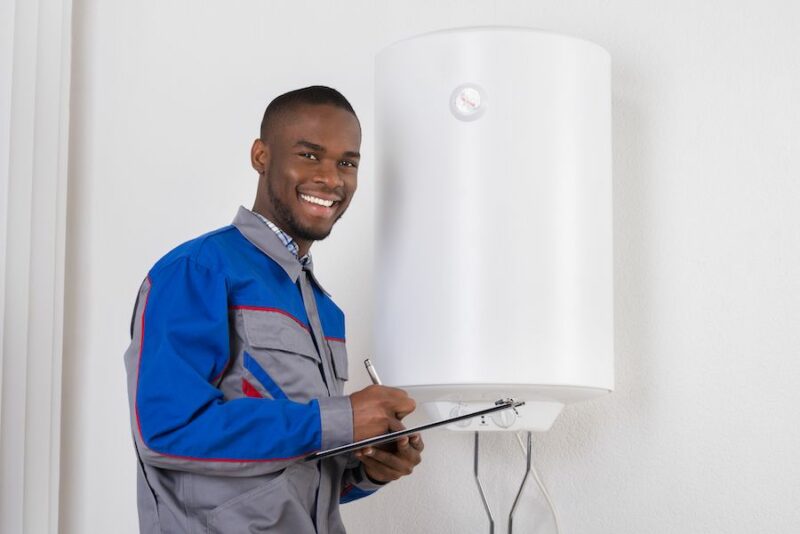 Image of technician standing next to boiler. How Do You Maintain Your Commercial Boiler?